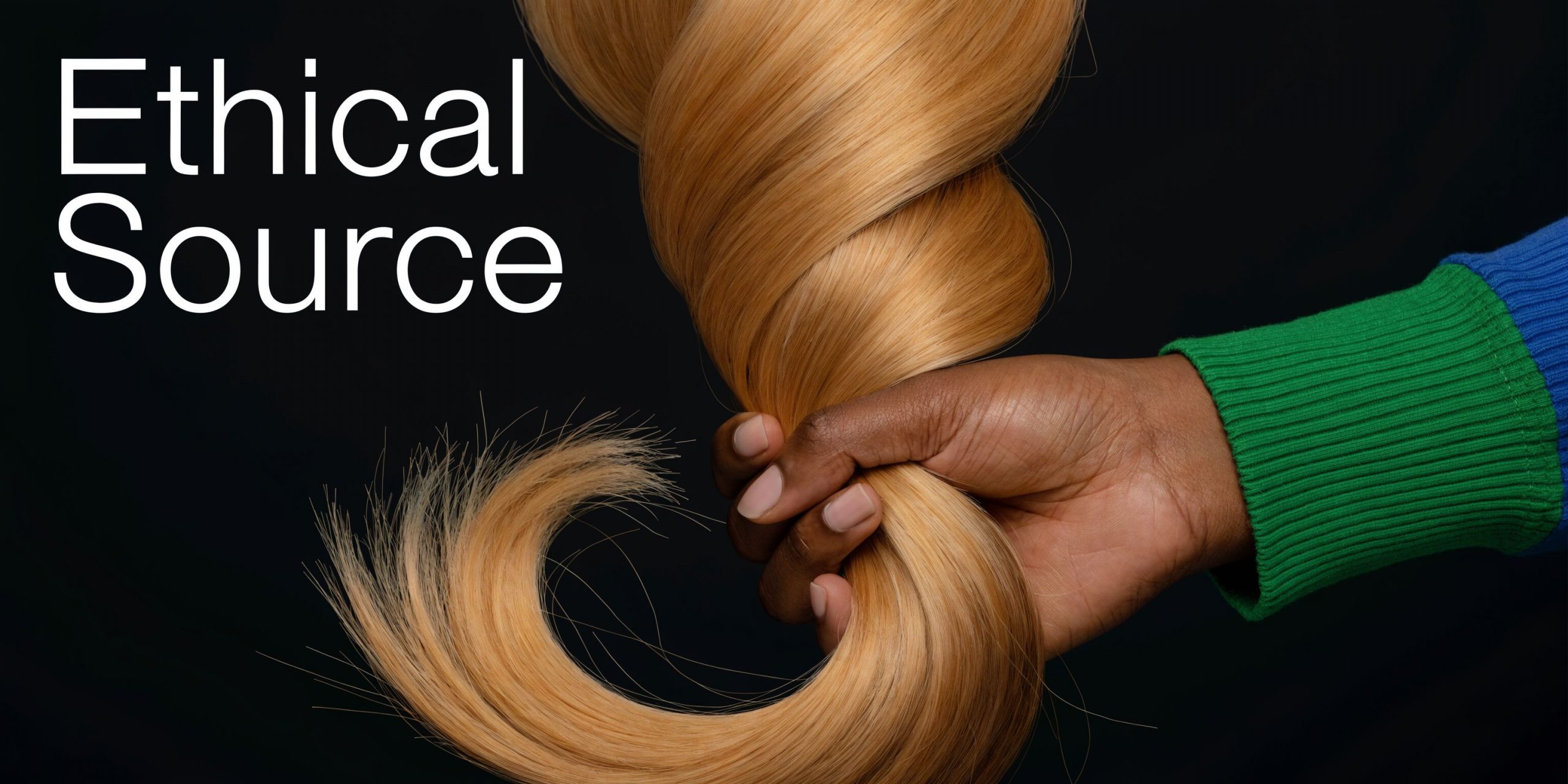 A hand holding a bundle of light blonde hair extensions against a solid black background.