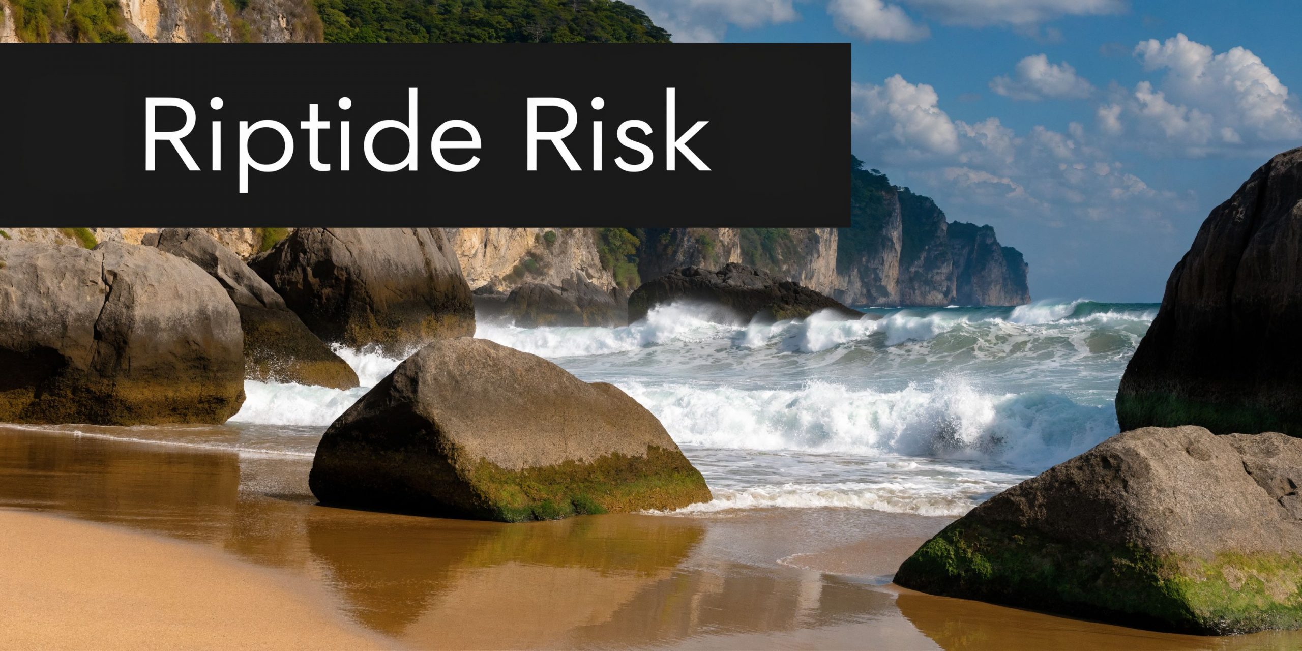 A scenic view of a sandy beach with large rocks and crashing waves under a blue sky.