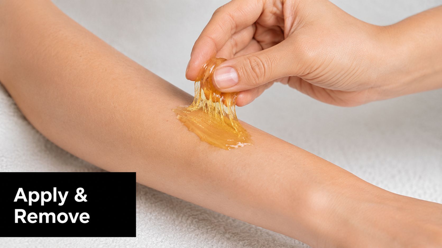 A close-up view of a hand applying and removing sugaring wax on a person's skin.
