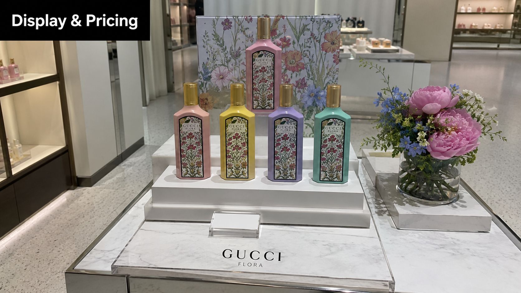 A luxurious display of colorful Gucci Flora perfume bottles arranged on white marble platforms in a store.